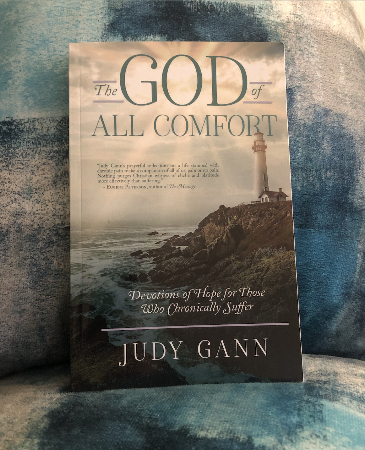 book "The God of All Comfort" by Judy Gann on a teal and gray background