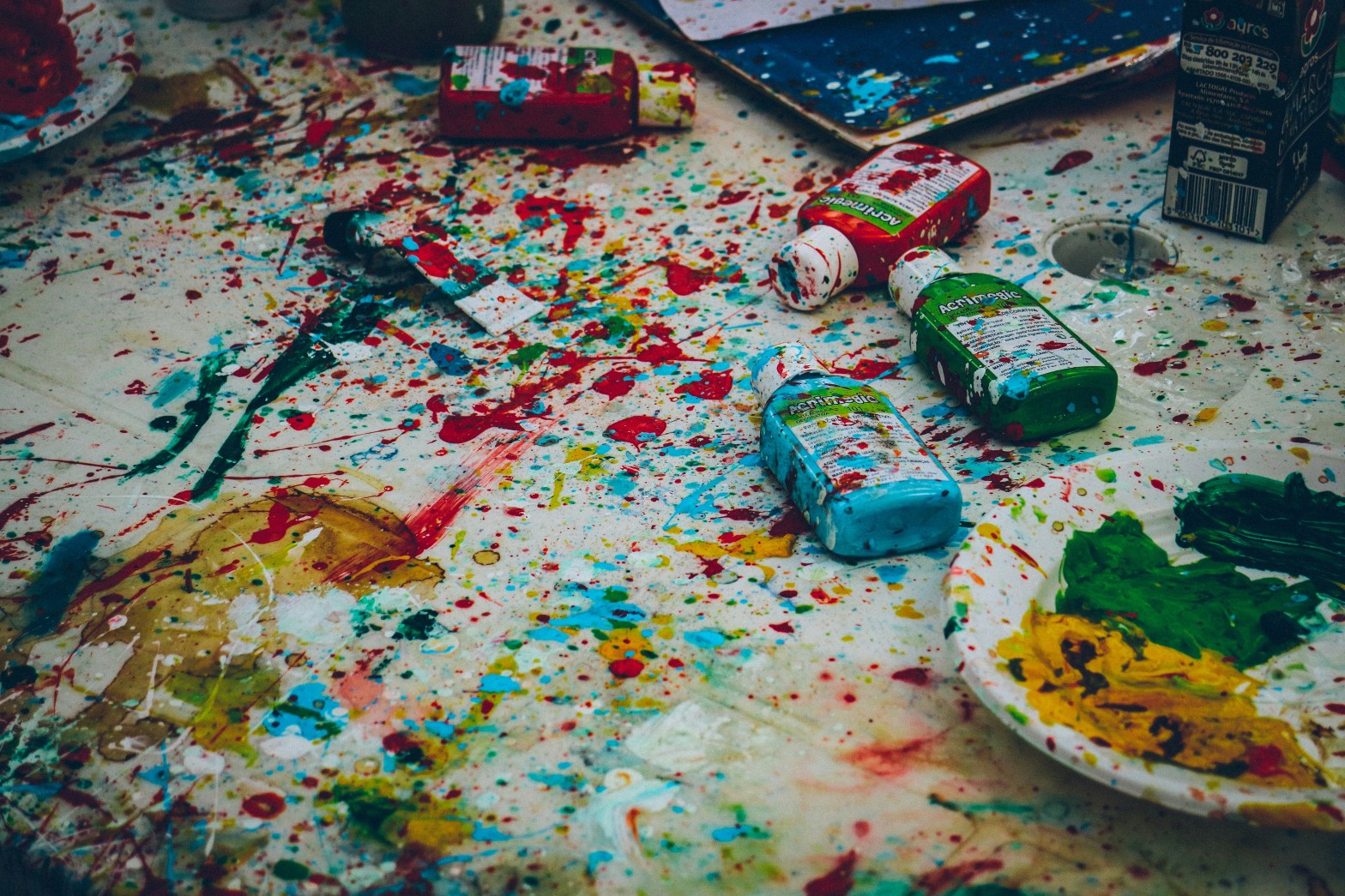 Multicolored paint splattered over surface, plates, paint bottles, etc.