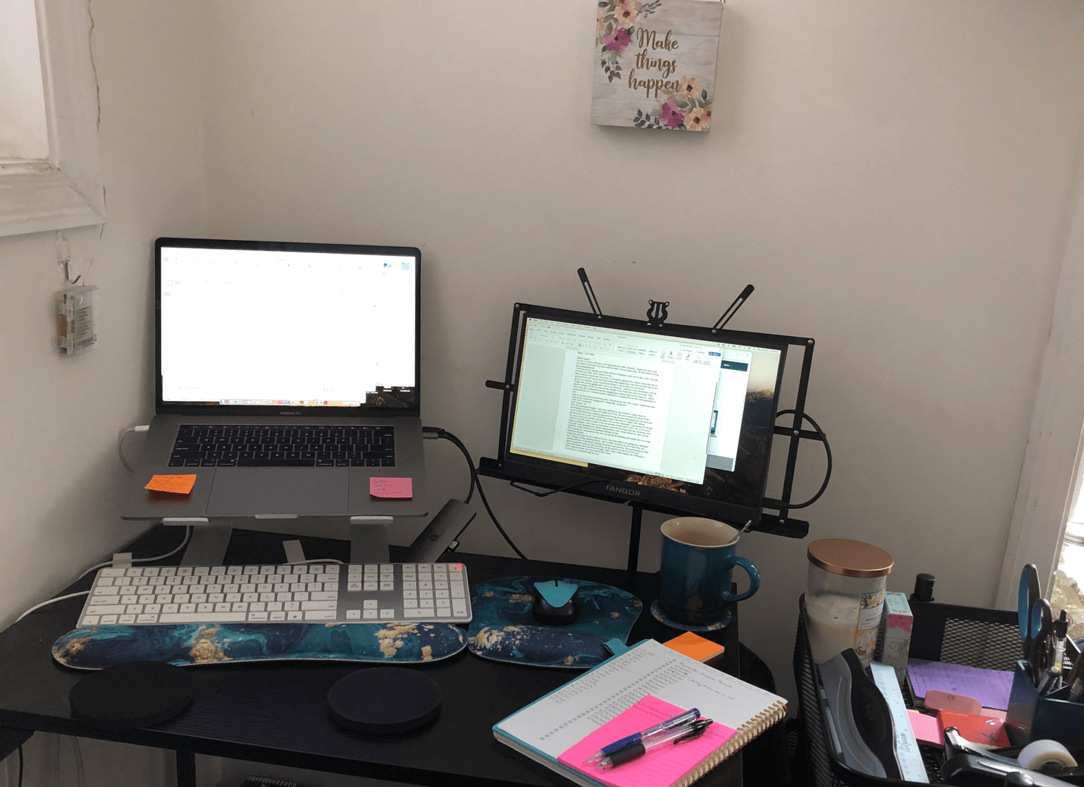 My work space, desk with raised laptop and second monitor, keyboard, mouse, notepad, mug, office supplies, and a plaque that reads "Make things happen"
